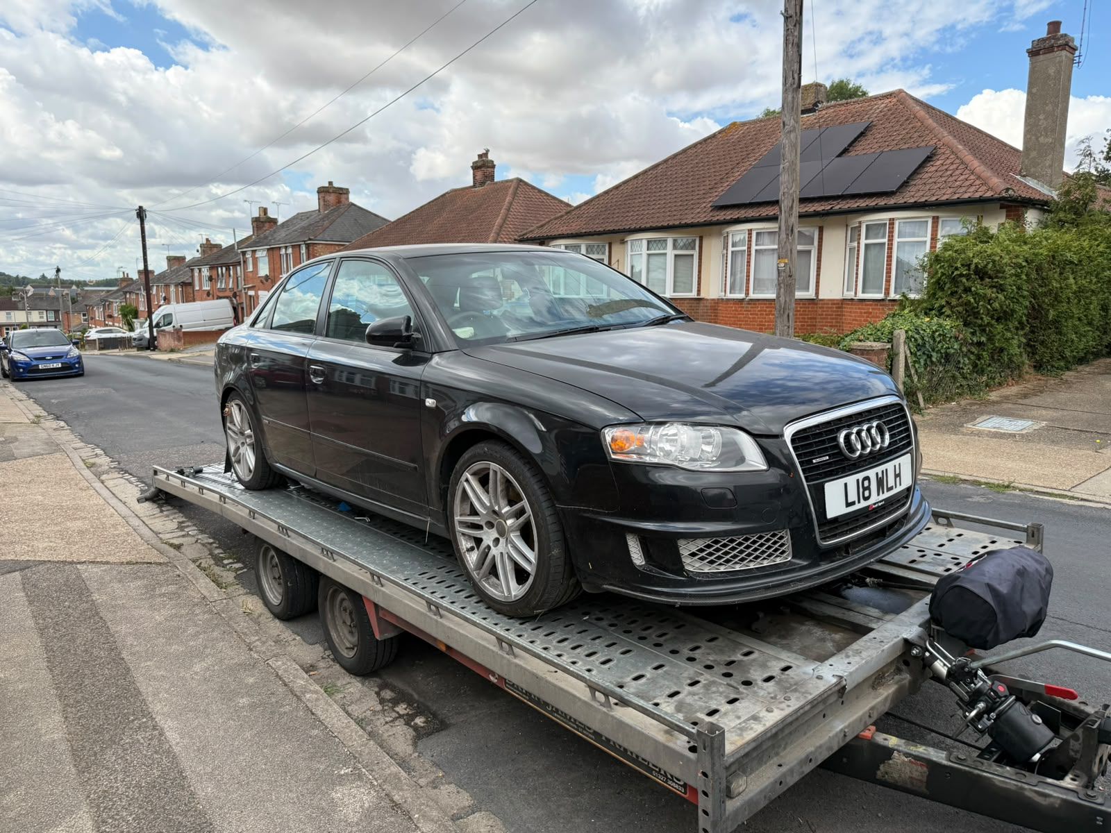 Black Audi A4 loaded on the SV Transport car transporter trailer on a residential street