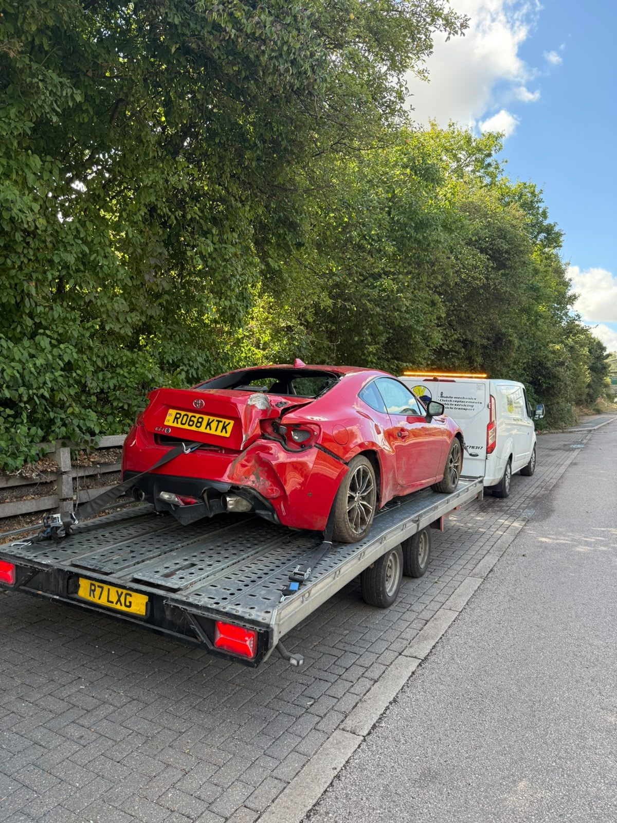 SV Transport recovery van towing a car transporter trailer with an accident-damaged red Toyota GT86